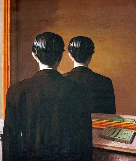 Two men in dark suits stand with their backs to the camera, facing a warm wall and a large mirror.