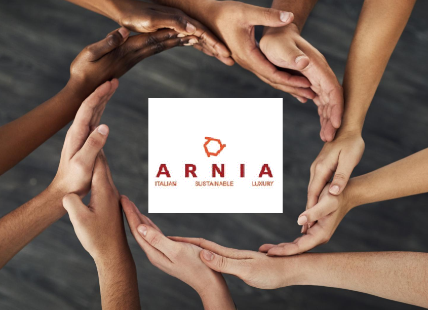Diverse hands join to form a circle around the ARNIA logo, symbolizing unity and sustainable luxury.